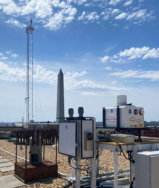 Scene on a flat top roof, Washington Monument in background. UrbanNet tower stands on the roof behind the LiDAR instrument in the foreground.
