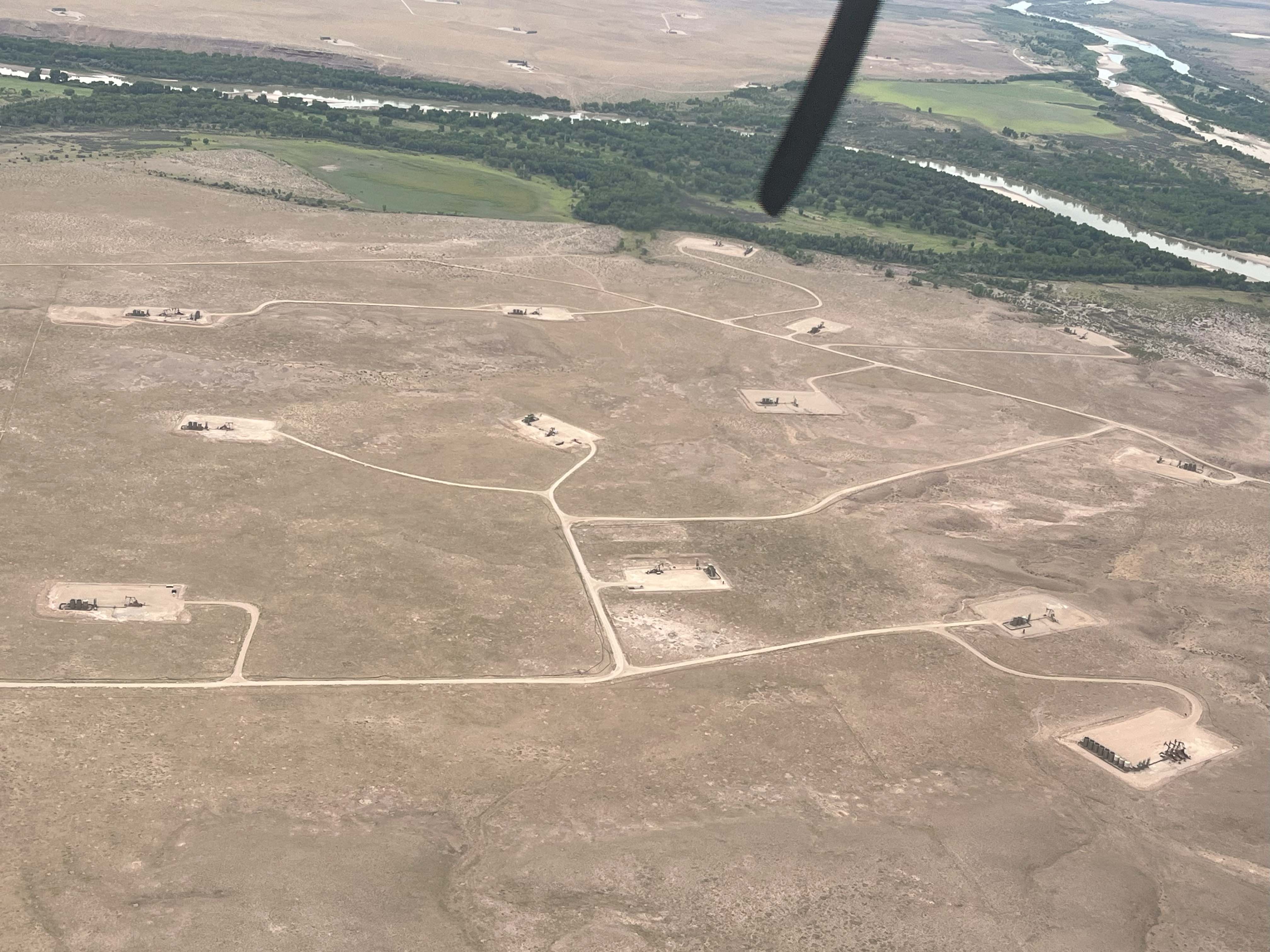 photo taken from a propeller plane of a barren landscape with a swath of green across the top of the image