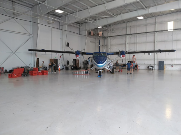 small propeller plane in the corner of a large hanger