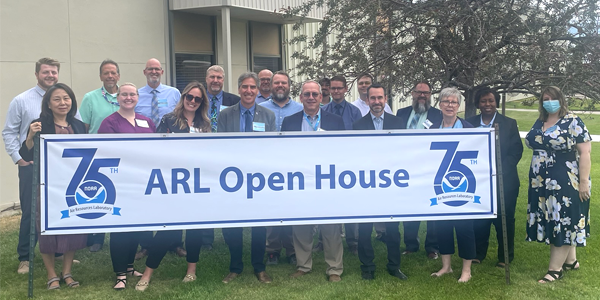 Group standing behind a banner that reads ARL Open House