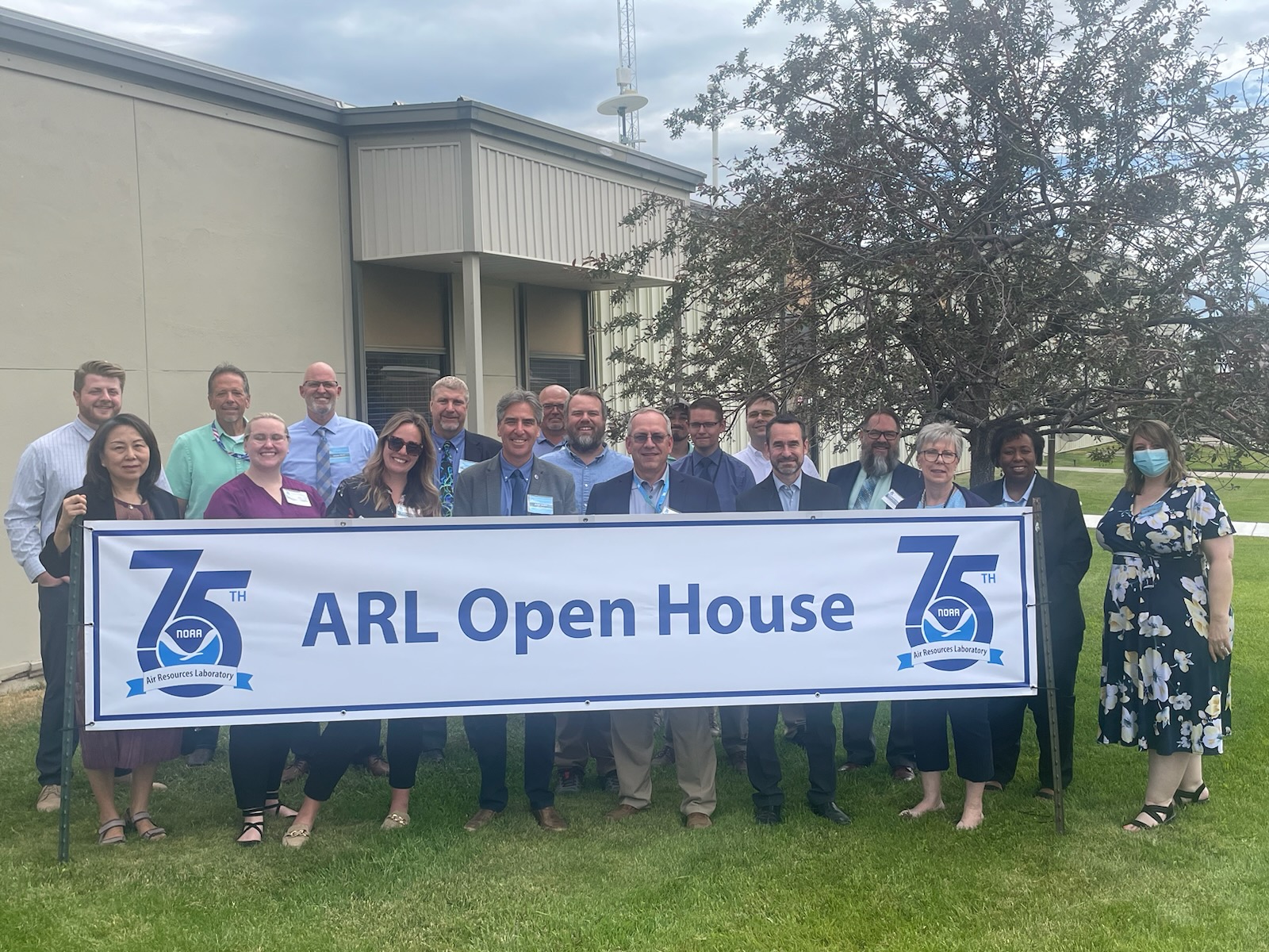 Group of people standing behind a banner that reads ARL Open House