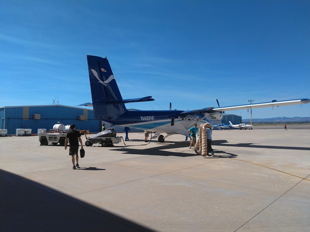 Man walking toward a small NOAA-branded propeller plane