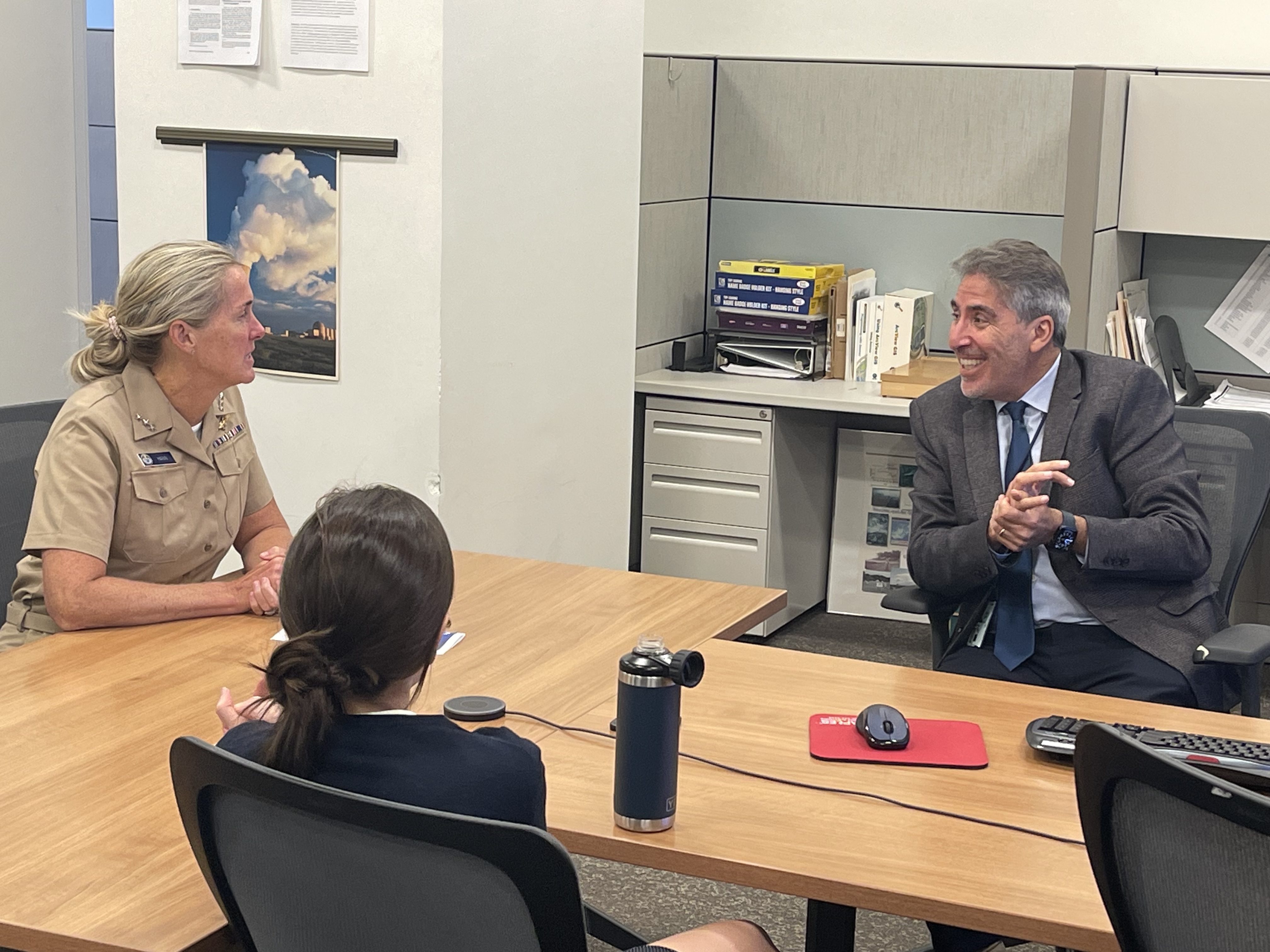 A man and two women sitting around a table in a conference room