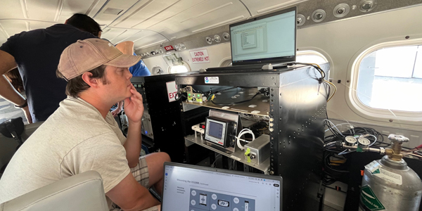 man looking at a laptop surrounded by scientific instruments