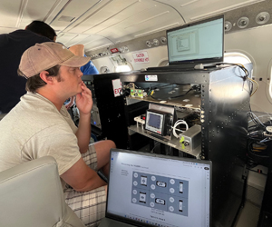 man looking at a laptop surrounded by scientific instruments